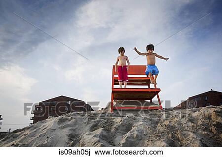 Two boys jumping off red notice board, Long Beach, New York State, USA View Large Photo Image Stock Image - Two boys jumping off red notice board, Long Beach, New York State, USA. Fotosearch