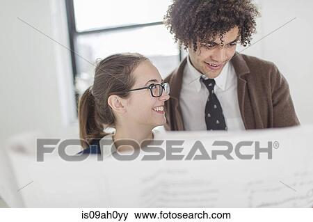 Stock Photo - Two colleagues discussing blueprint. Fotosearch