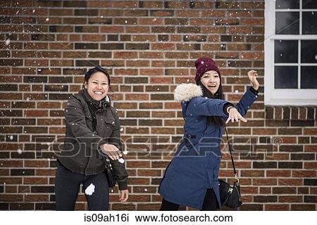 Stock Image - Two you adult females throwing snowballs. Fotosearch
