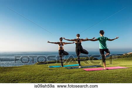 Stock Image - Women on cliff, in yoga position. Fotosearch