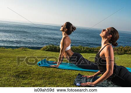Stock Image - Women on cliff, in yoga position. Fotosearch