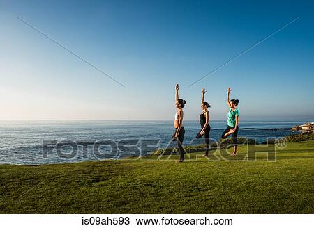 Stock Image - Women on cliff, in yoga positions. Fotosearch
