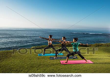 Stock Image - Women on cliff, in yoga positions. Fotosearch