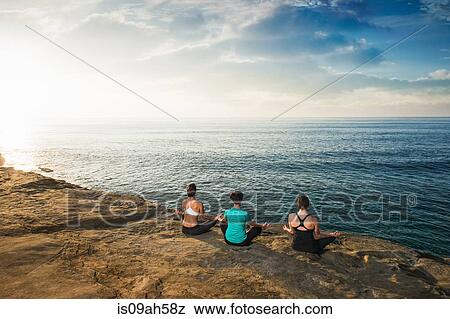 Women sitting on cliff top, looking at sea and meditating View Large Photo Image Stock Photo - Women sitting on cliff top, looking at sea and meditating. Fotosearch