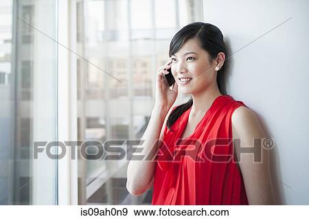 Stock Photo - Young businesswoman chatting on cellphone in office. Fotosearch