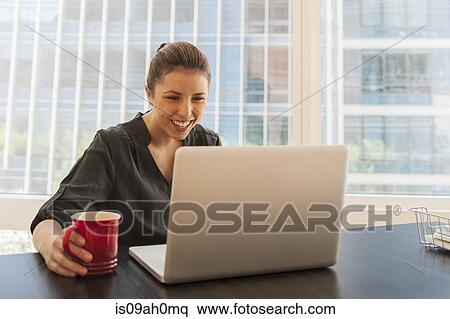 Young businesswoman taking a coffee break in office View Large Photo Image Stock Photography - Young businesswoman taking a coffee break in office. Fotosearch