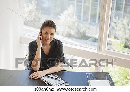 Young businesswoman talking on cellphone in office View Large Photo Image Stock Photo - Young businesswoman talking on cellphone in office. Fotosearch
