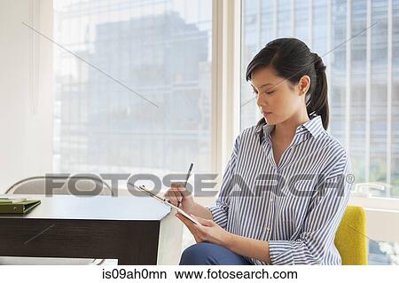 Young businesswoman working on paperwork in office View Large Photo Image Picture - Young businesswoman working on paperwork in office. Fotosearch
