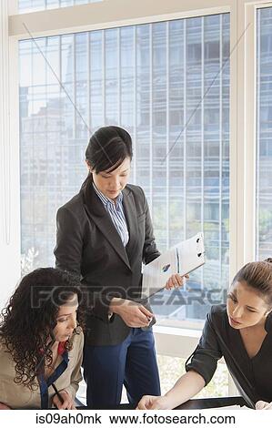 Stock Image - Young businesswomen meeting in office. Fotosearch