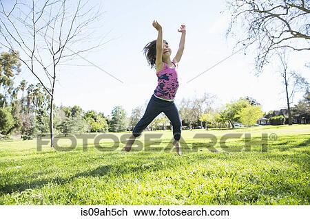 Young girl jumping mid air in park View Large Photo Image Stock Image - Young girl jumping mid air in park. Fotosearch