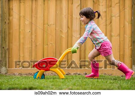 Young girl running with toy wheelbarrow in the garden View Large Photo Image Picture - Young girl running with toy wheelbarrow in the garden. Fotosearch
