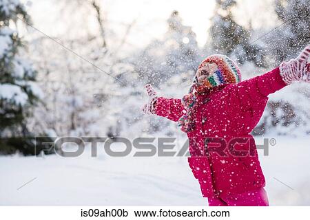 Stock Image - Young girl shouting and throwing snow mid air. Fotosearch
