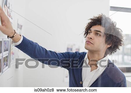 Young man looking at images on wall View Large Photo Image Stock Photo - Young man looking at images on wall. Fotosearch