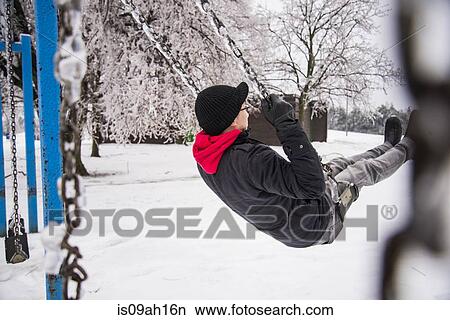 Young man playing on park swing at -30 degrees celcius View Large Photo Image Picture - Young man playing on park swing at -30 degrees celcius. Fotosearch