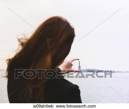 Young woman aligning fingers with statue of liberty, New York, USA View Large Photo Image Stock Image - Young woman aligning fingers with statue of liberty, New York, USA. Fotosearch