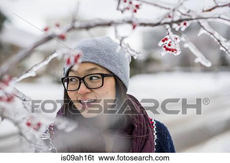 Stock Photograph - Young woman and ice covered tree branches. Fotosearch