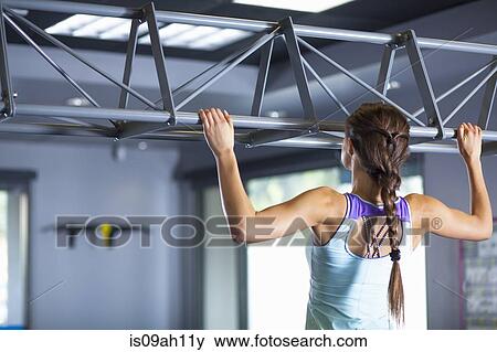 Stock Photo - Young woman doing chin ups. Fotosearch