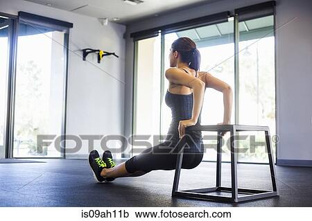 Stock Image - Young woman doing push ups. Fotosearch