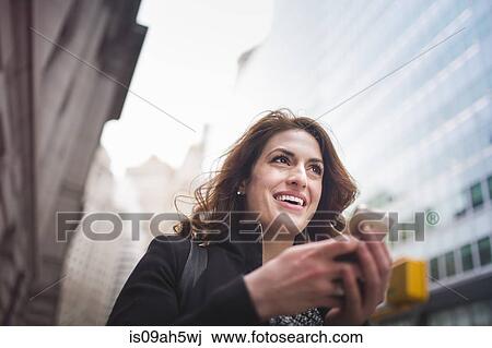 Stock Image - Young woman holding cellphone, New York, USA. Fotosearch