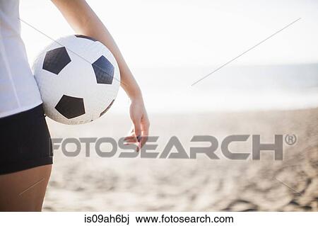 Stock Image - Young woman holding football. Fotosearch