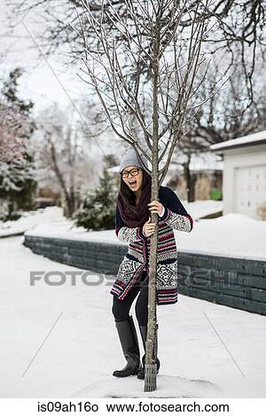 Young woman holding onto tree in slippy snow View Large Photo Image Picture - Young woman holding onto tree in slippy snow. Fotosearch
