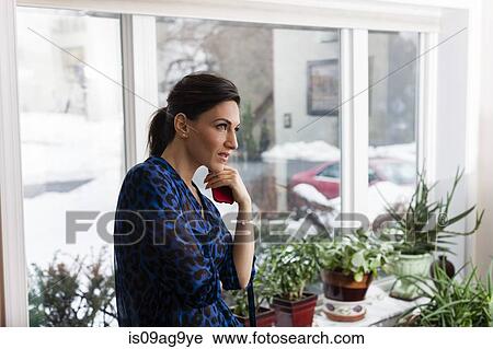 Young woman in sitting room holding cellphone View Large Photo Image Stock Image - Young woman in sitting room holding cellphone. Fotosearch