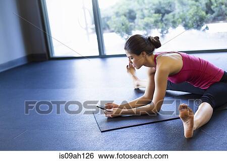 Stock Photograph - Young woman in yoga posture using cellular phone. Fotosearch