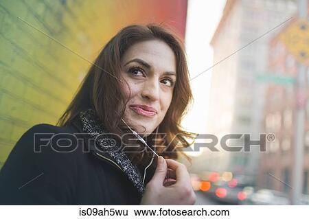 Young woman listening to earphones on city street View Large Photo Image Stock Photograph - Young woman listening to earphones on city street. Fotosearch