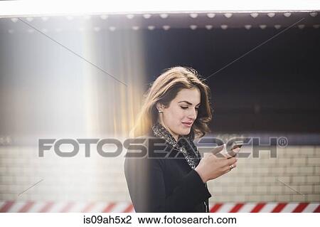 Young woman looking at cellphone in subway station View Large Photo Image Stock Image - Young woman looking at cellphone in subway station. Fotosearch