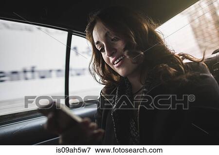 Young woman looking at cellphone in taxi View Large Photo Image Stock Photo - Young woman looking at cellphone in taxi. Fotosearch