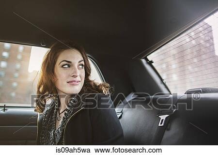 Stock Image - Young woman looking back from taxi. Fotosearch