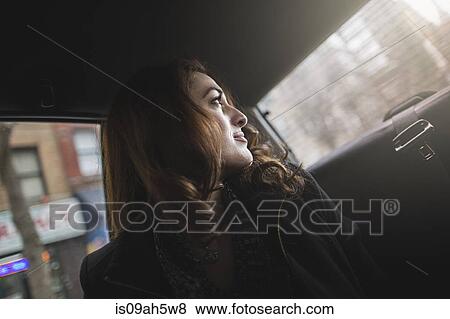 Stock Photo - Young woman looking over her shoulder from taxi. Fotosearch