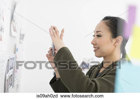 Young woman photographing images on wall View Large Photo Image Stock Image - Young woman photographing images on wall. Fotosearch