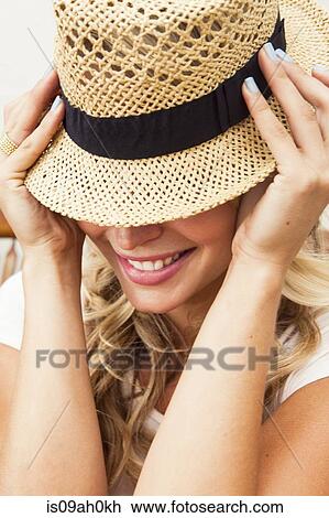 Young woman putting on straw hat View Large Photo Image Stock Image - Young woman putting on straw hat. Fotosearch