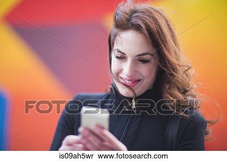 Young woman reading text messages on city street View Large Photo Image Stock Photography - Young woman reading text messages on city street. Fotosearch