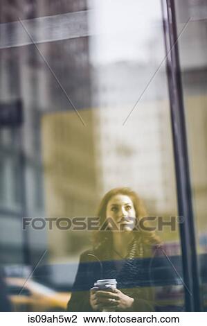 Stock Image - Young woman reflected in shop window. Fotosearch