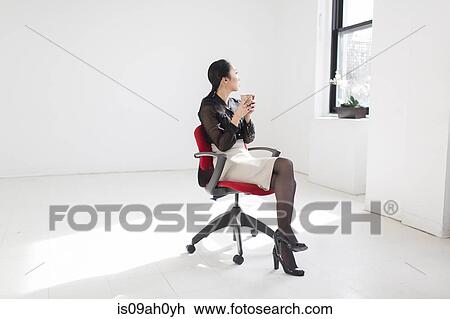 Young woman sitting on office chair with coffee View Large Photo Image Stock Image - Young woman sitting on office chair with coffee. Fotosearch