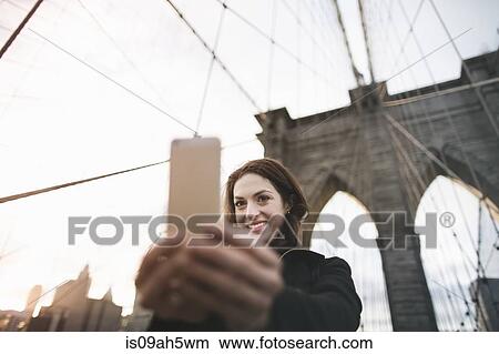 Young woman taking selfie on Brooklyn bridge, New York, USA View Large Photo Image Picture - Young woman taking selfie on Brooklyn bridge, New York, USA. Fotosearch