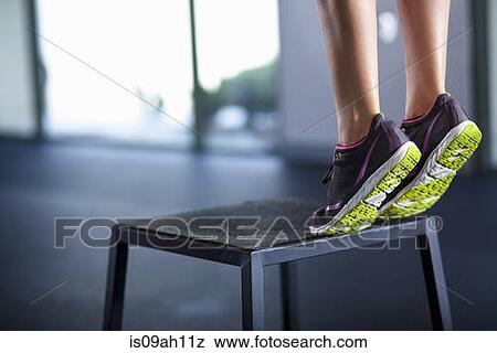 Young woman tiptoeing on edge of stool View Large Photo Image Stock Photo - Young woman tiptoeing on edge of stool. Fotosearch