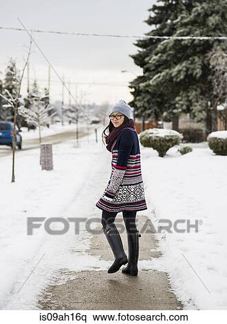Stock Photography - Young woman walking down snow covered street. Fotosearch
