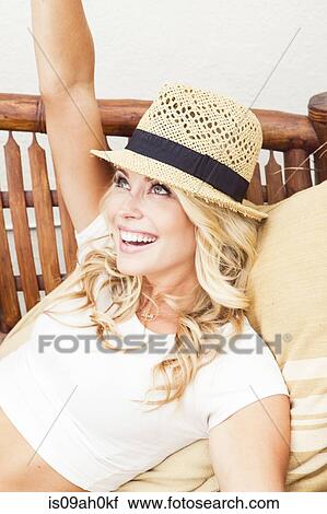 Stock Image - Young woman wearing straw hat looking up. Fotosearch