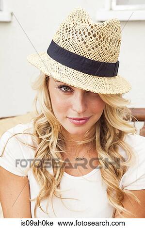 Stock Image - Young woman wearing straw hat. Fotosearch