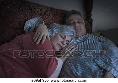 Affectionate mature adult couple sleeping on bed View Large Photo Image Picture - Affectionate mature adult couple sleeping on bed. Fotosearch