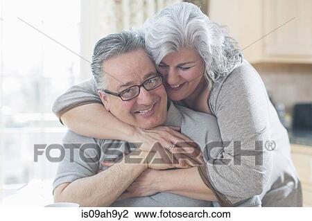 Affectionate mature adult couple hugging at home View Large Photo Image Stock Image - Affectionate mature adult couple hugging at home. Fotosearch