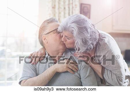 Affectionate mature adult couple kissing at home View Large Photo Image Stock Image - Affectionate mature adult couple kissing at home. Fotosearch