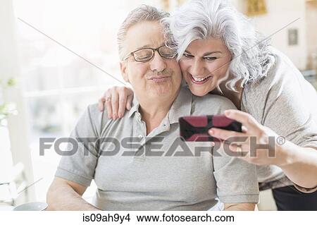 Affectionate mature adult couple taking a self portrait at home View Large Photo Image Picture - Affectionate mature adult couple taking a self portrait at home. Fotosearch