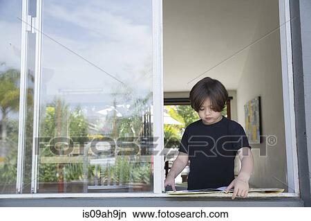 Picture - Boy reading his book at open window. Fotosearch