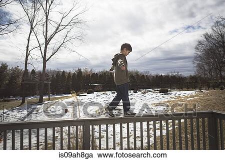 Boy walking along top of fence in park View Large Photo Image Stock Image - Boy walking along top of fence in park. Fotosearch