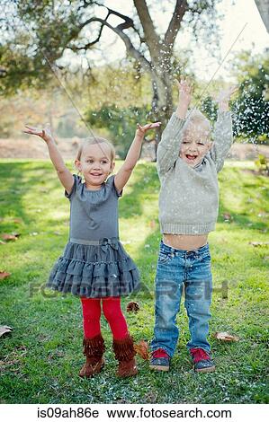 Brother and sister with arms raised, in garden View Large Photo Image Stock Image - Brother and sister with arms raised, in garden. Fotosearch