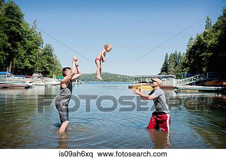 Stock Photography - Female toddler thrown and caught mid air by young men. Fotosearch